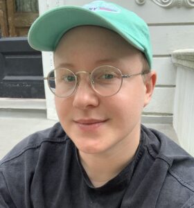 Cary wearing glasses and a green cap 